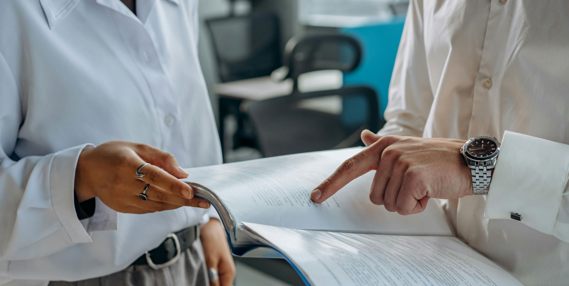 Colleagues Standing in White Long Sleeve Shirts Discussing and Reading a Financial Report